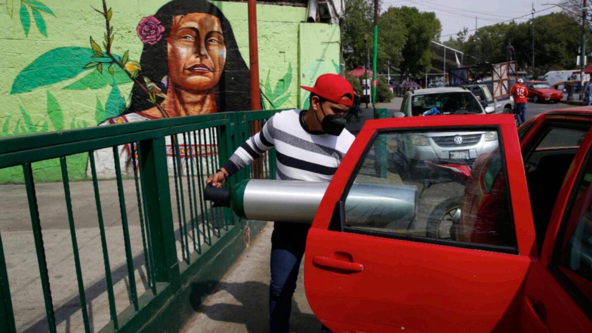 A person loads into the back seat of a car a tank filled with oxygen for a family member sick with Covid-19, in the Iztapalapa borough of Mexico City. The city offers free oxygen refills for Covid-19 patients. — AP