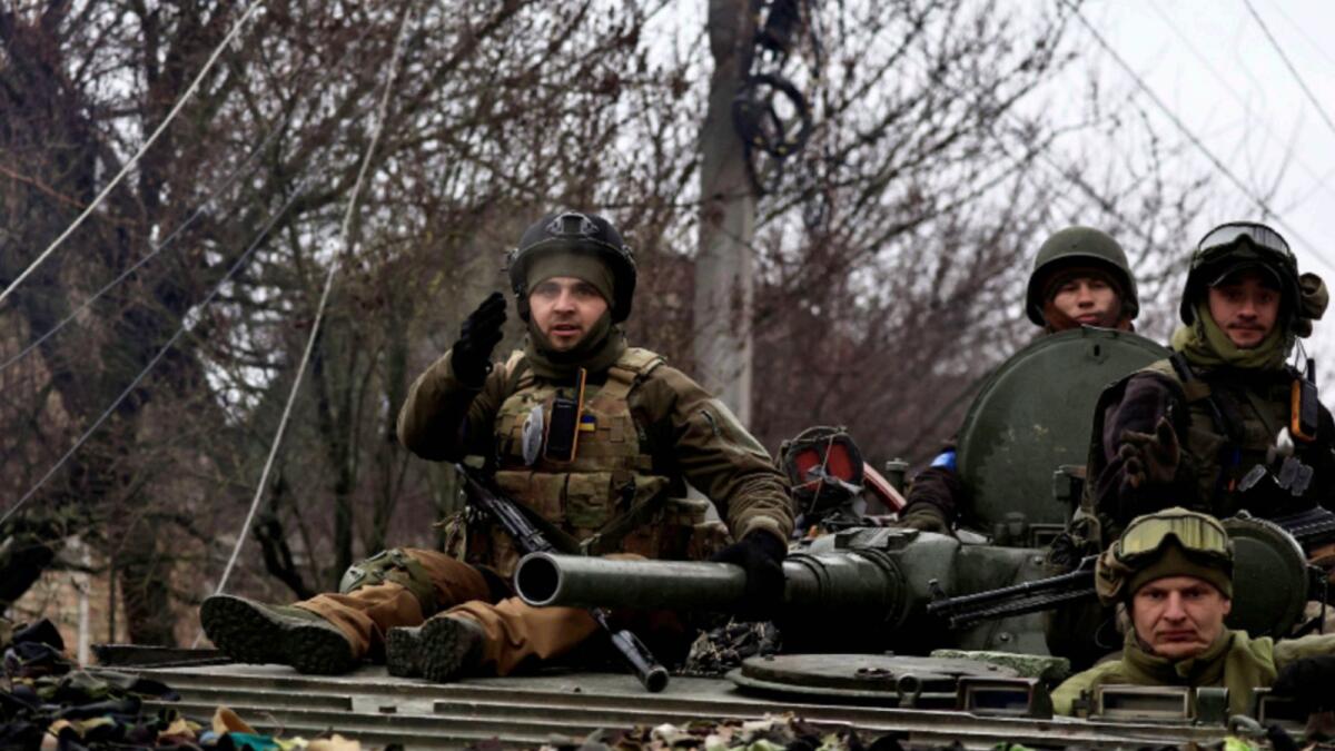 Ukrainian soldiers sit on a tank in Bucha. — Reuters