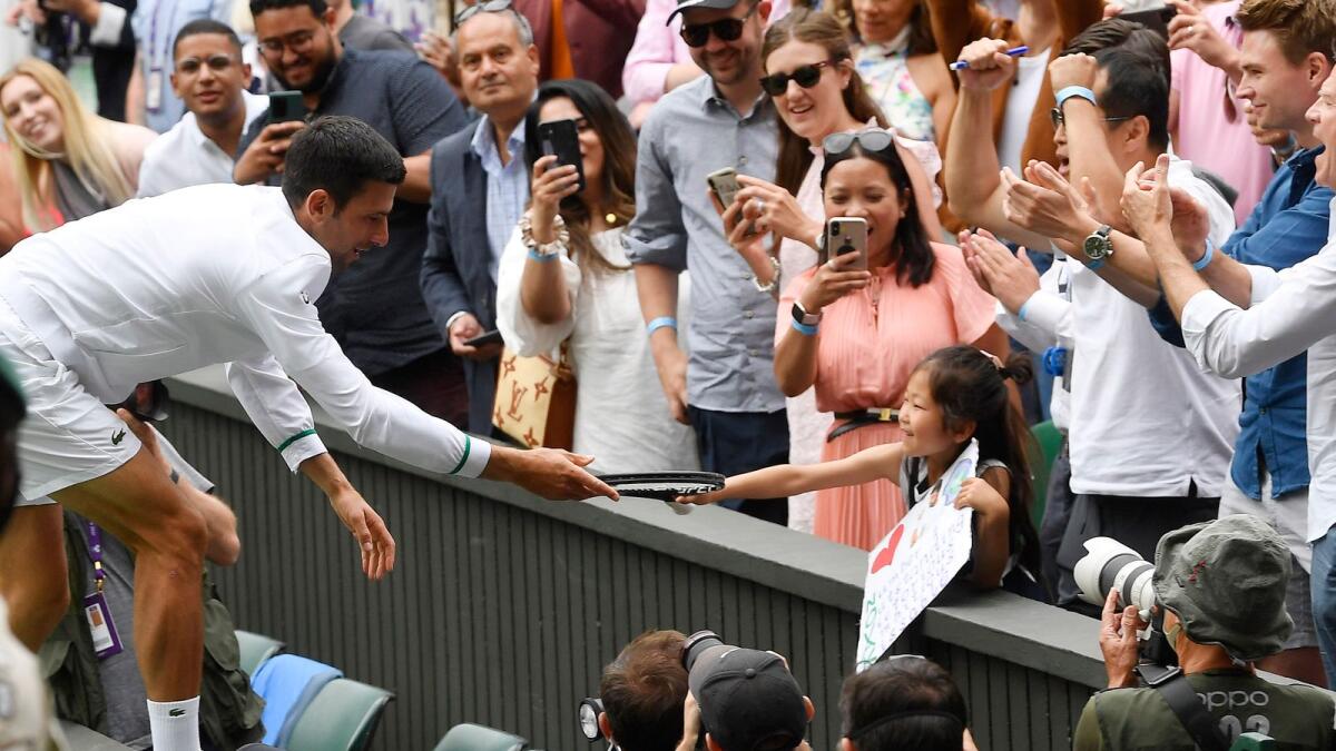 Tennis - Wimbledon - All England Lawn Tennis and Croquet Club, London, Britain - July 11, 2021 Serbia's Novak Djokovic signs an autograph for a fan after winning his final match against Italy's Matteo Berrettini REUTERS/Toby Melville