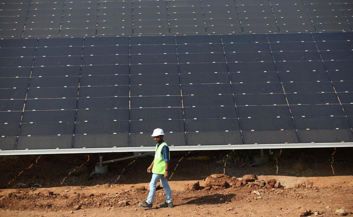 An official walks past solar panels installed at the Pavagada Solar Park north of Bangalore, India, March 1, 2018. — AP file