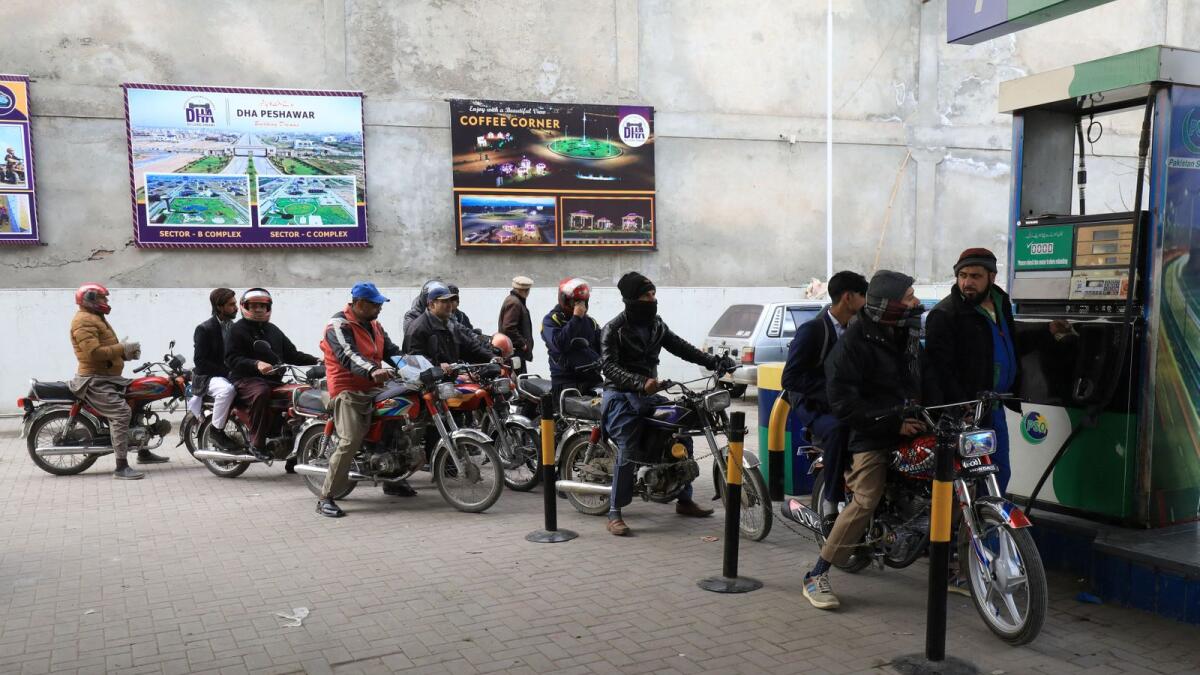 People wait for their turn to get fuel at a petrol station in Peshawar, Pakistan. — Reuters file