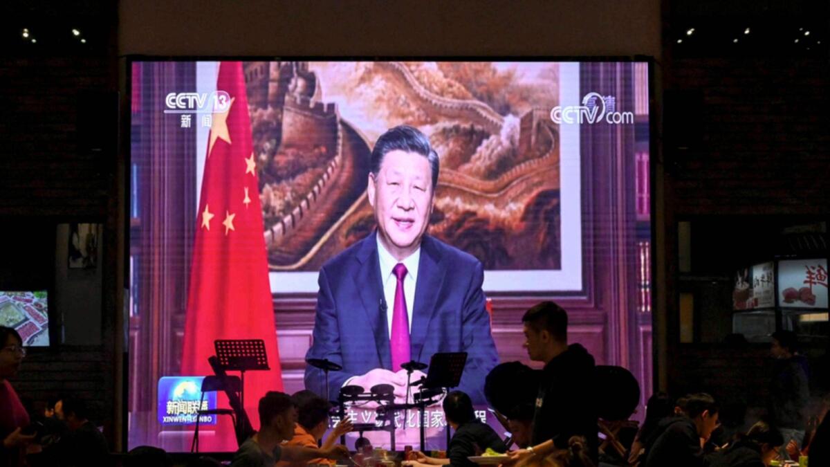 People have their dinner at a restaurant as a screen broadcasts Chinese President Xi Jinping delivering his New Year speech in Beijing. — AFP