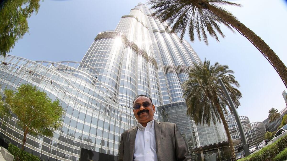 George V Neryamparampil, the owner of 22 apartments, on different floors of Burj Khalifa poses for a photograph in front of Burj Khalifa.