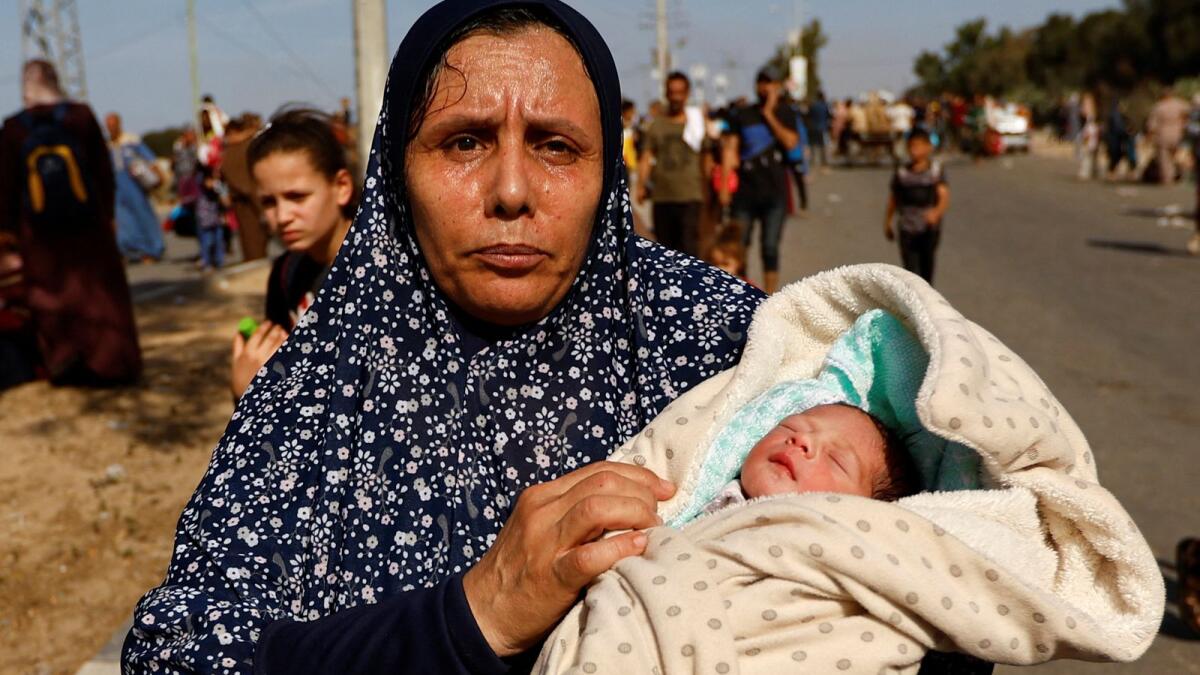 Palestinian woman Um Hussein holds her granddaughter, who she said was born today, while she moves southward after fleeing north Gaza as Israeli tanks roll deeper into the enclave, November 10, 2023. Reuters