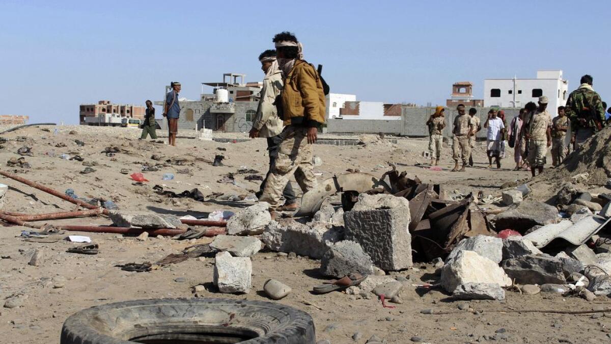Soldiers gather the site of a suicide bomb at a base in the southern city of Aden, Yemen