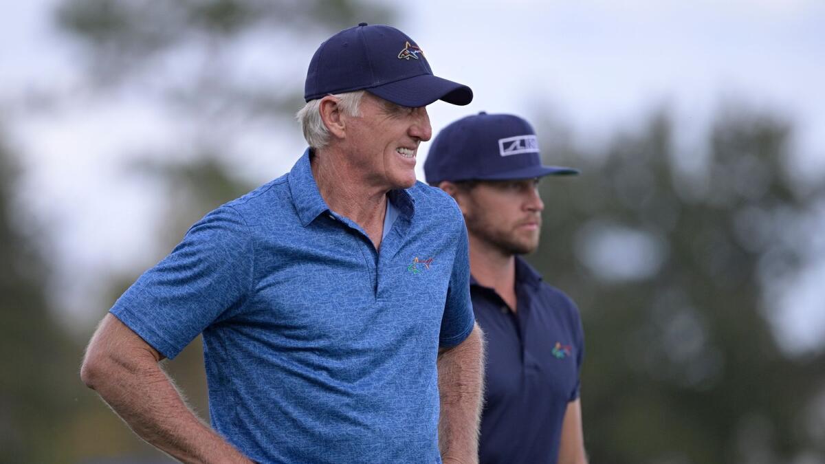 Greg Norman(left) of Australia, walks with his son Greg Norman Jr. on the 18th fairway after hitting their tee shots during the the PNC Championship golf tournament, in Orlando, Florida. — AP