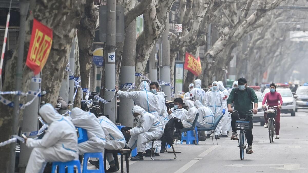 Workers are seen wearing protective clothes next to some lockdown areas after the detection of new cases of covid-19 in Shanghai on March 14, 2022. Photo: AFP