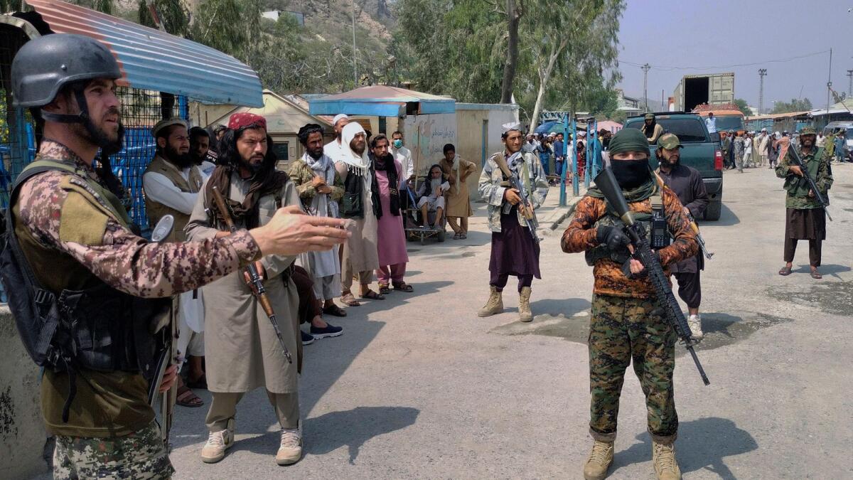 A Pakistani paramilitary soldier (left) and Taliban fighters stand guard on their respective sides at a border crossing point between Pakistan and Afghanistan. — AP file