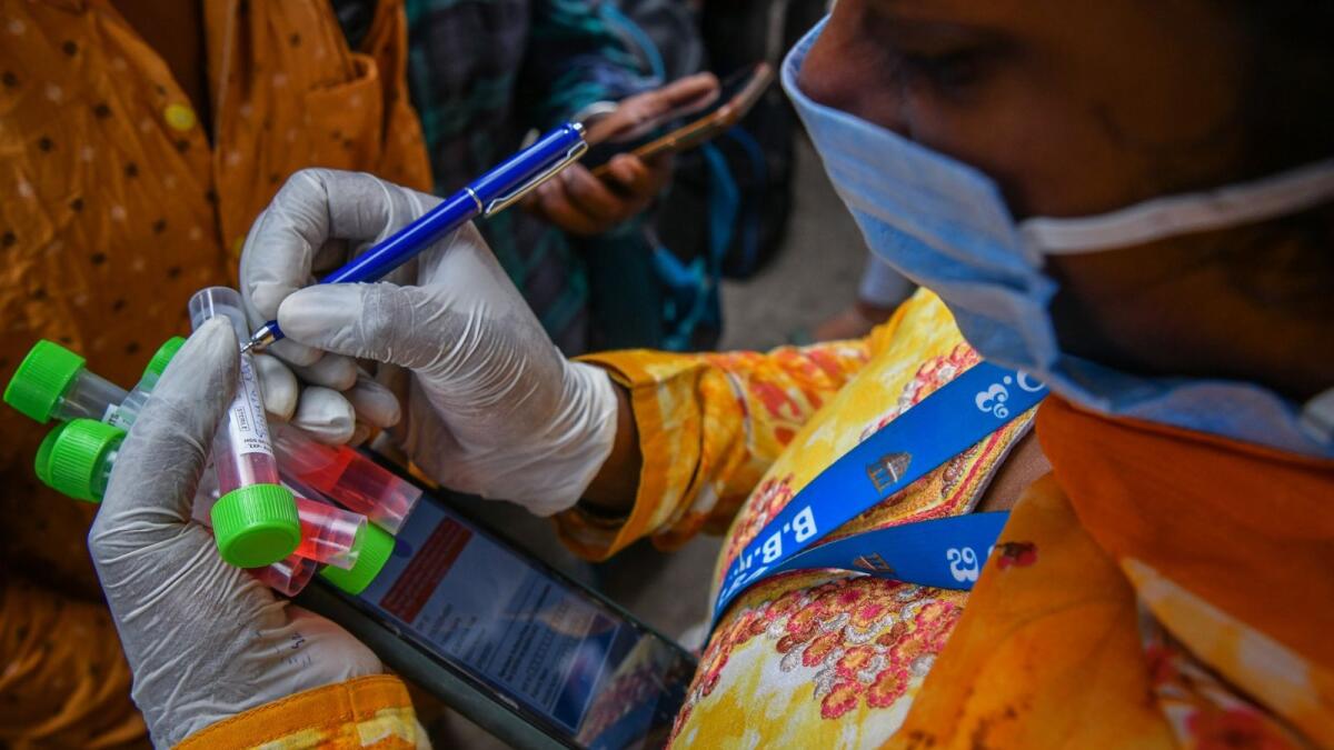 A health official gathers details before conducting Covid-19 coronavirus screening during an enforcement drive in Bangalore. – AFP