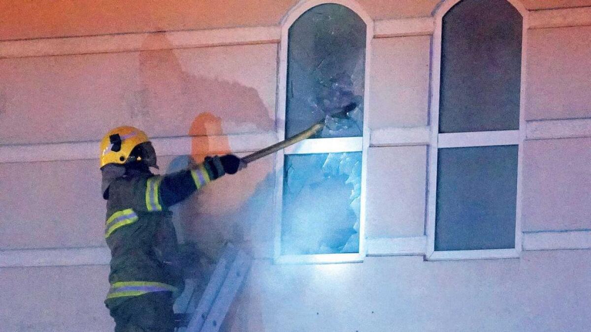 A firefighter uses his axe to break open a window after a fire broke out in Al Manama Supermarket  at a 19-floor building on Sharjah’s Al Arouba Street on Friday evening. 