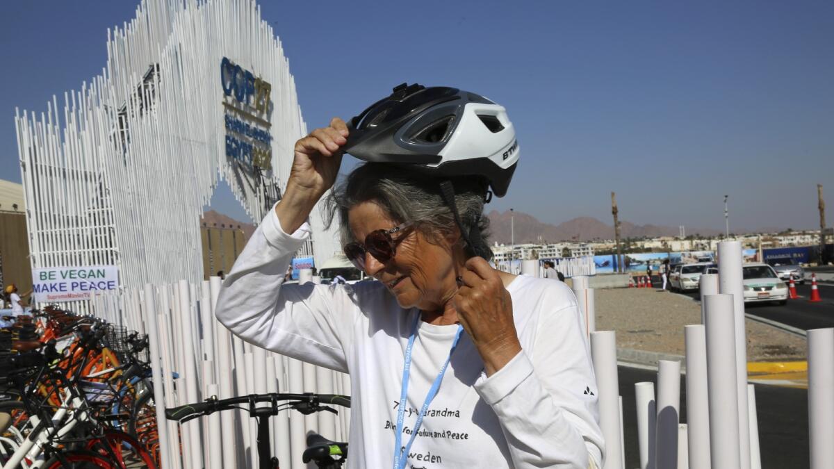 Dorothee Hildebrandt, 72, removes her bike helmet after arriving to the UN.climate summit COP27 venue in Sharm El Sheikh, Egypt, on Saturday. — AP