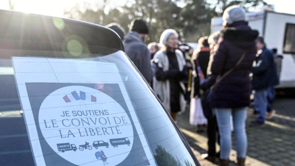 Participants of the 'Freedom Convoy' (Convoi de la Liberte) stand past a sticker on a car rear windowshield reading 'I support Freedom Convoy' on the roadside outside the Canadian memorial of Vimy, in Vimy northern France. — AFP