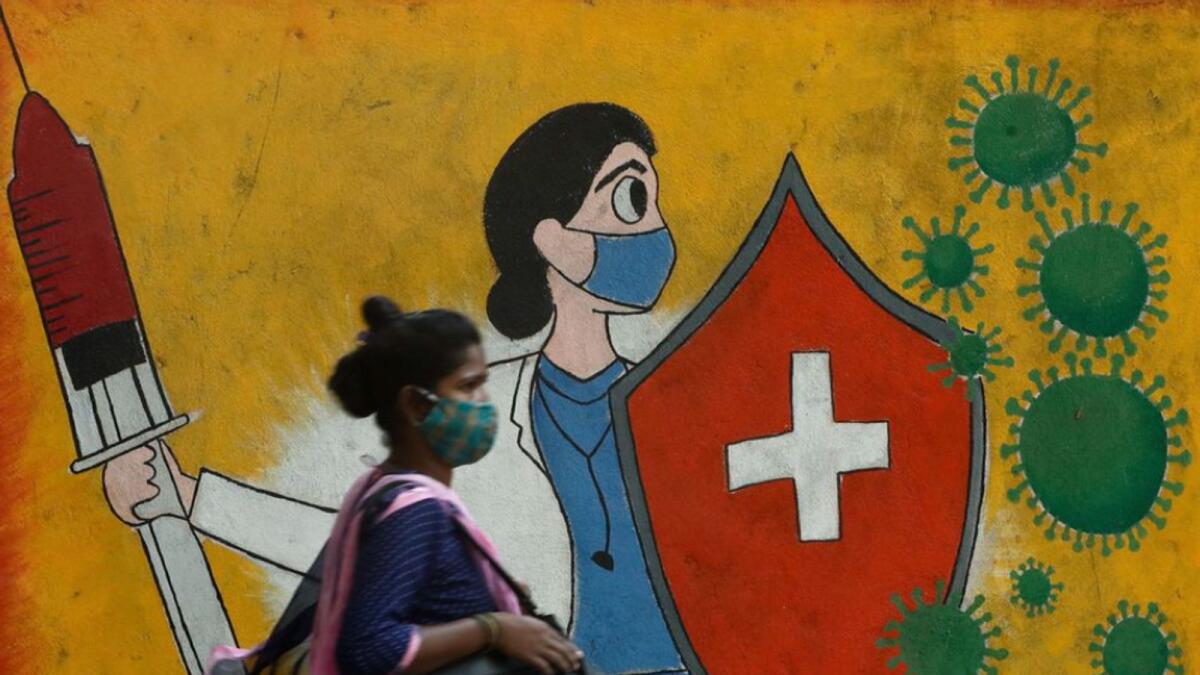A woman walks past a graffiti on a street, amidst the spread of Covid-19 in Mumbai, India.