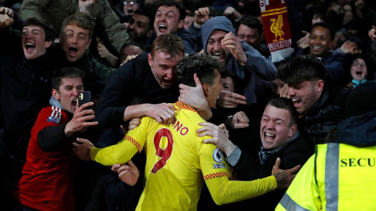 Liverpool's Roberto Firmino celebrates with fans after scoring the second goal against Arsenal at the Emirates Stadium in London on Wednesday. — AFP
