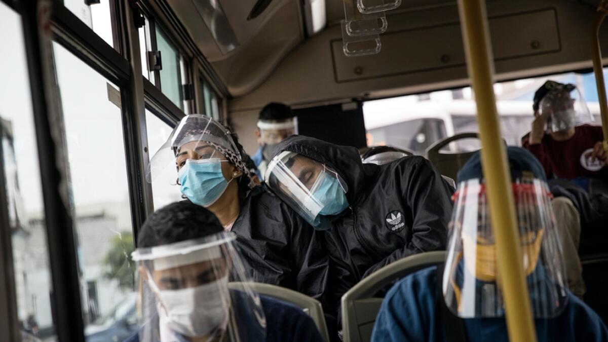 Commuters using plastic face protectors travel in a public bus in Lima, Peru. The government declares the use of plastic face protectors mandatory for public transport passengers. Photo: AP