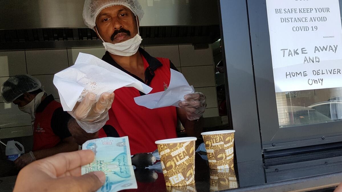 A cafeteria staff delivers tea and snacks to a customer in Garhoud, Dubai. Cafeteria and restaurants now have to follow strict guidelines put in place by the Dubai Municipality and the Dubai Health Authority.