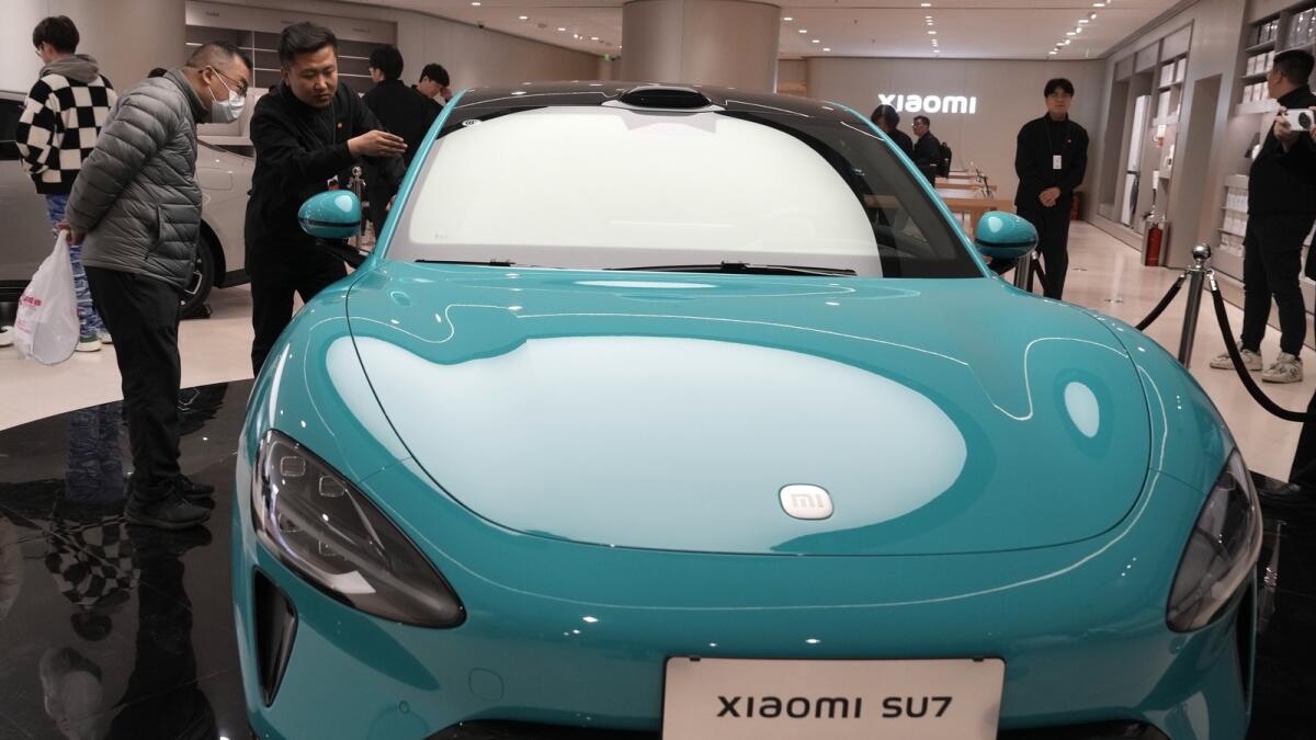 Visitors to the Xiaomi Automobile flagship store look at the Xiaomi SU7 electric car on display in Beijing. — AP