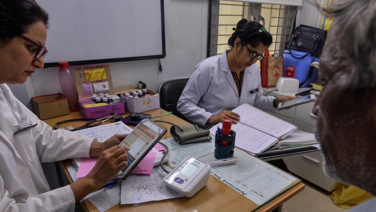 An Indian doctor prescribes medical tests and medicines as she examines patients at a clinic in New Delhi. - AFP PHOTO
