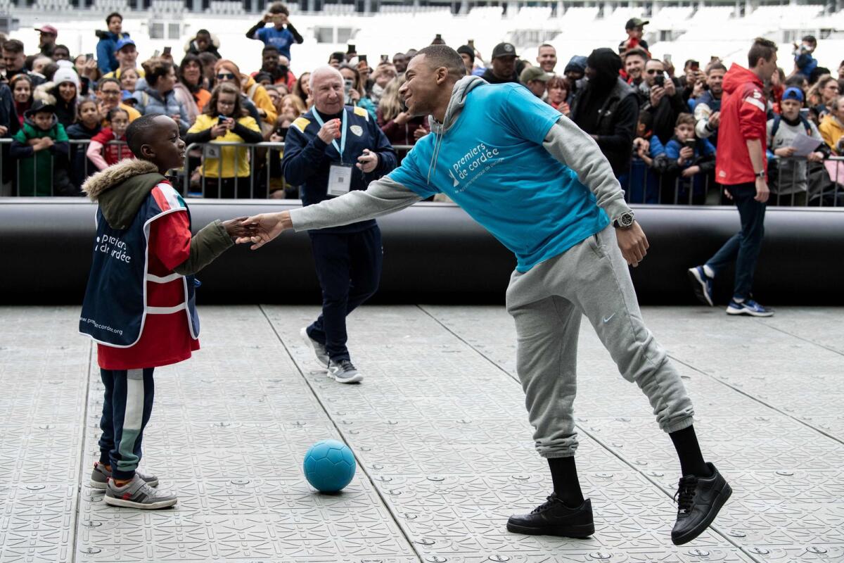 Paris Saint-Germain's Kylian Mbappe shakes a child's hand as he takes part in a football match with children from the 'Premiers de Cordee' association at the Stade de France on Wednesday. — AFP