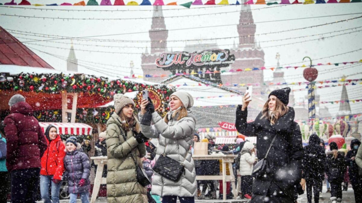 Visitors take selfie pictures at the Christmas and New Year market in front of the Kremlin's Spasskaya Tower at the Red Square in Moscow. — AFP