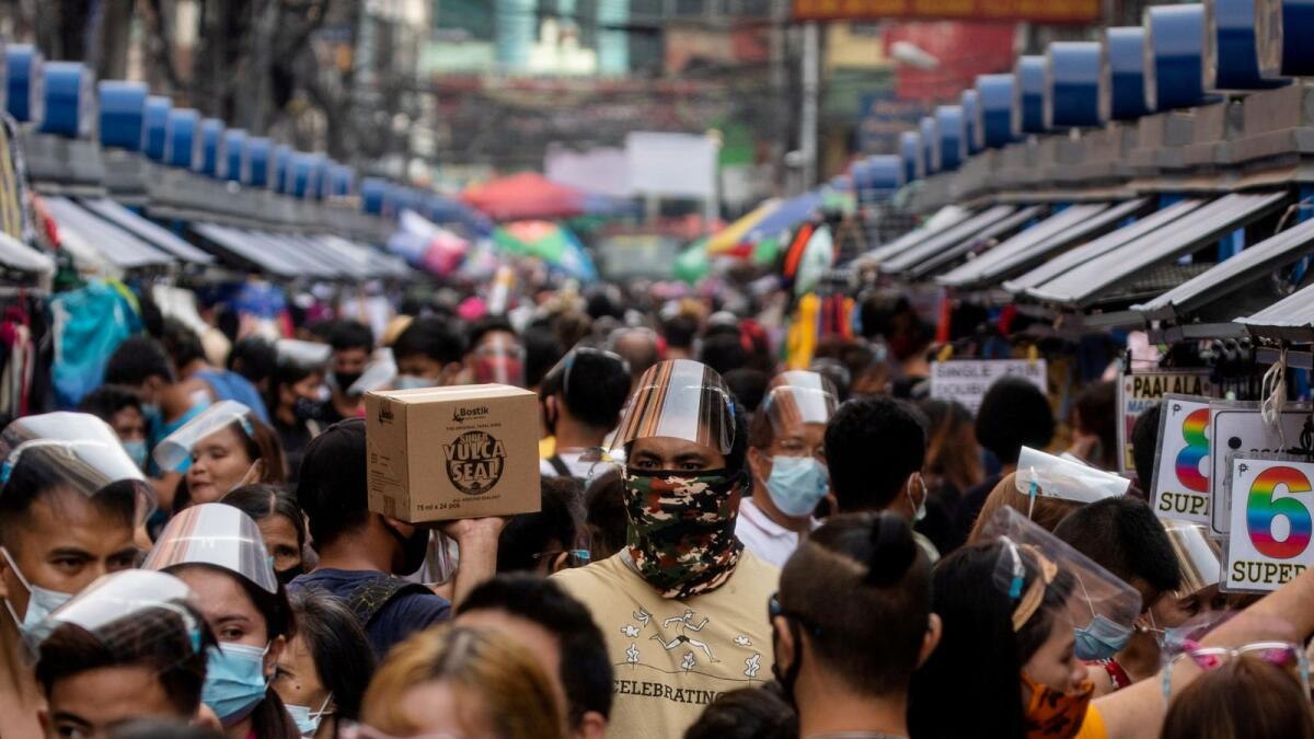 Filipinos wearing masks and face shields for protection against the coronavirus disease (COVID-19) walk along a street market in Manila, Philippines, December 3, 2020.