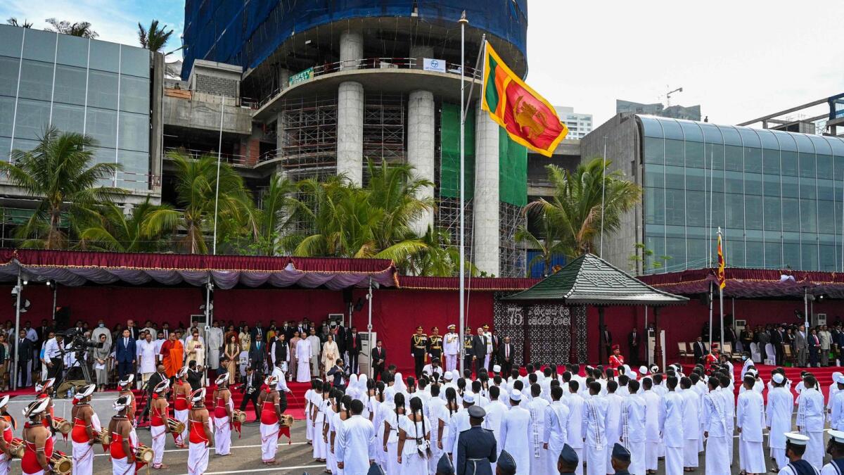 Sri Lanka's President Ranil Wickremesinghe (on R next to mast) listens to the national anthem during the Sri Lanka's 75th Independence Day celebrations in Colombo on Saturday. — AFP