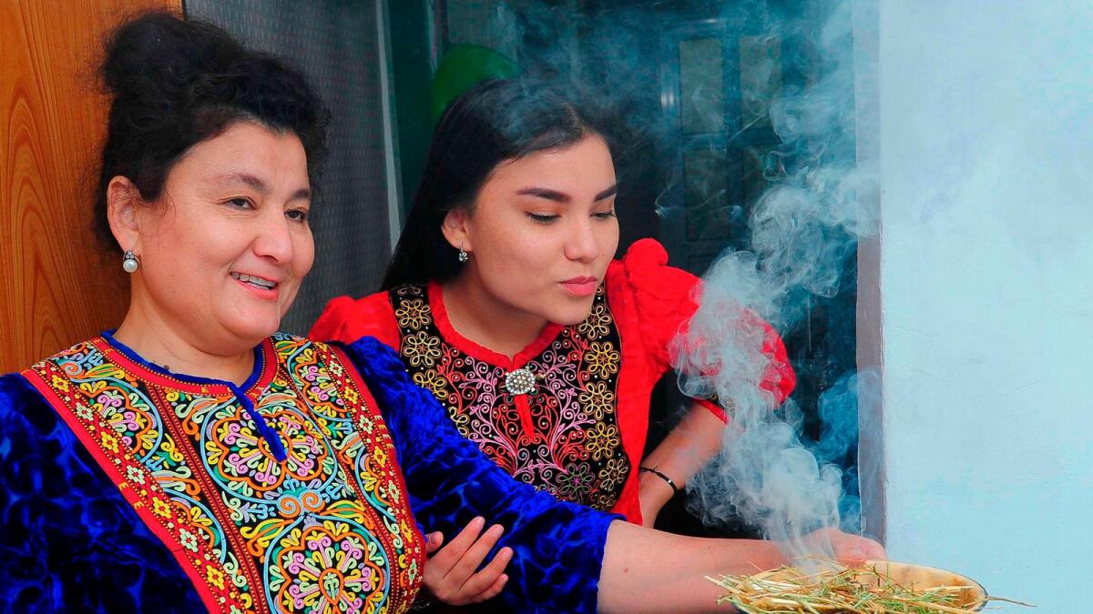 Turkmen women wearing traditional dress demonstrate how to fumigate a house with the smoke of burning wild rue (known locally as yuzerlik) in Ashgabat.