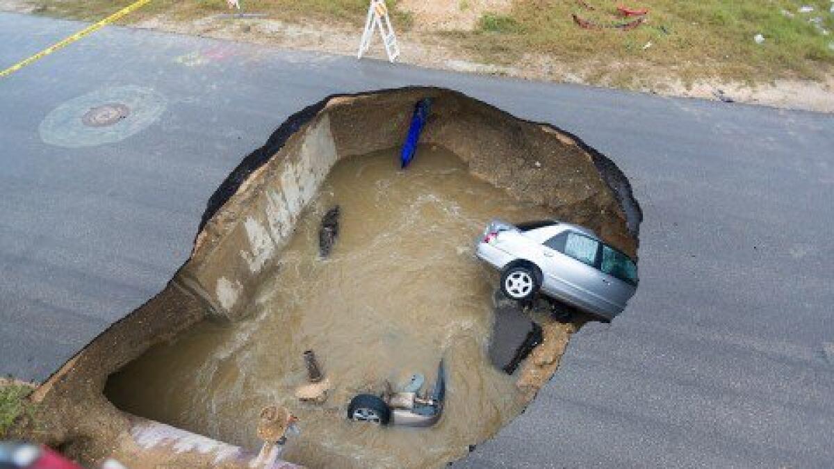 Massive sinkhole swallows two cars, leaving one dead