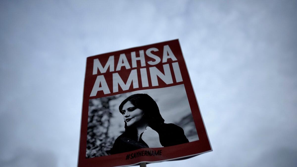 A woman holds a placard with a picture of Mahsa Amini during a protest against her death, in Berlin, Germany, on September 28, 2022. — AP