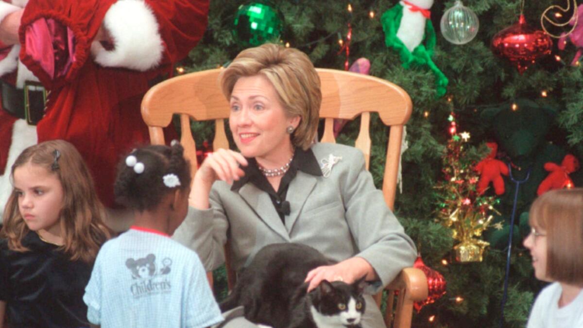 Hillary Rodham Clinton pets Socks the cat on her lap as she talks with children at the Children's National Medical Center in Washington on Dec. 15, 1999. — AP file