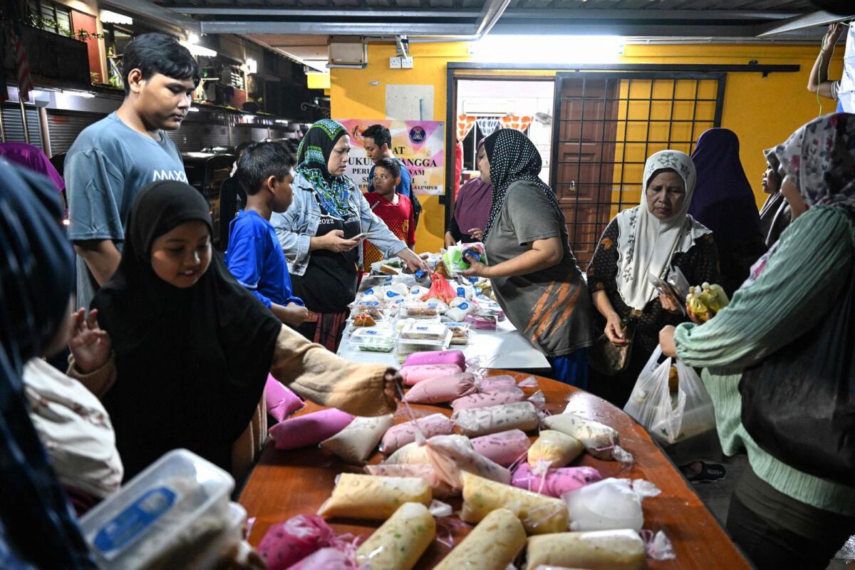 Residents receive unsold food collected from street markets by volunteers of the NGO GEMA Malaysia in the Keramat neighbourhood of Kuala Lumpur during the holy month of Ramadan on March 18, 2024. — AFP