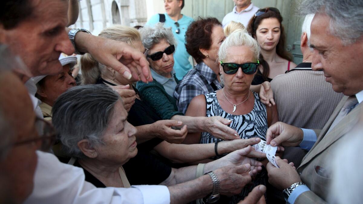 Pensioners are given priority tickets by a National Bank branch manager (R), as they wait to receive part of their pensions in Athens, Greece July 13, 2015. Euro zone leaders clinched a deal with Greece on Monday to negotiate a third bailout to keep the near-bankrupt country in the euro zone after a whole night of haggling at an emergency summit.   REUTERS/Yiannis Kourtoglou