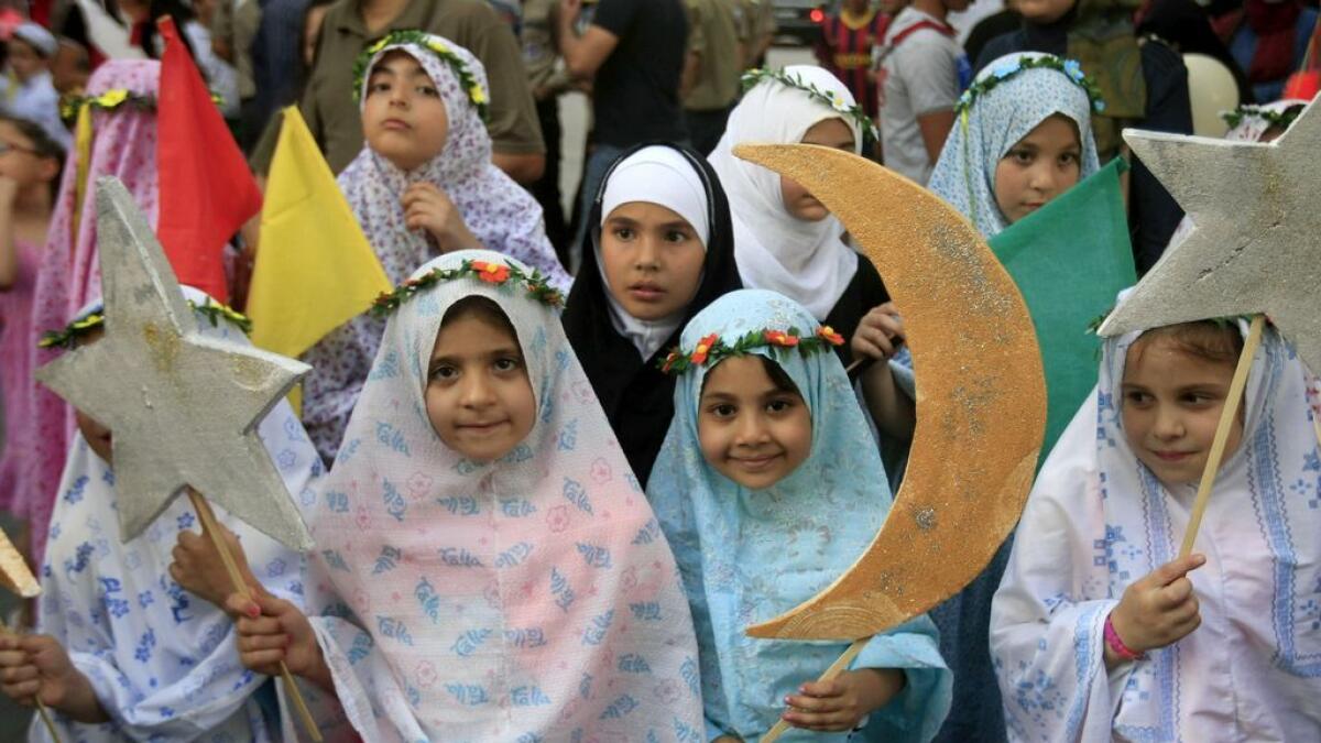 Lebanese girls hold crescents and stars during street performances celebrating the upcoming Muslim holy month of Ramadan, in the southern port city of Sidon, Lebanon
