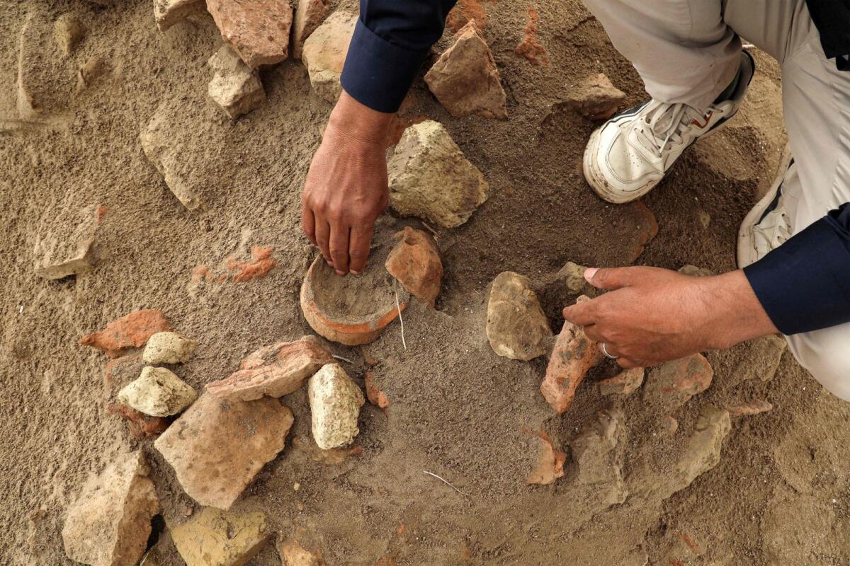 Archaeologist Aqeel Mansarawi searches for pottery sherds at the Umm Al Aqarib archaeological site, frequently buried by sandstorms due to desertification, in the district of Al Rifai in Iraq's southern Dhi Qar province. -- AFP