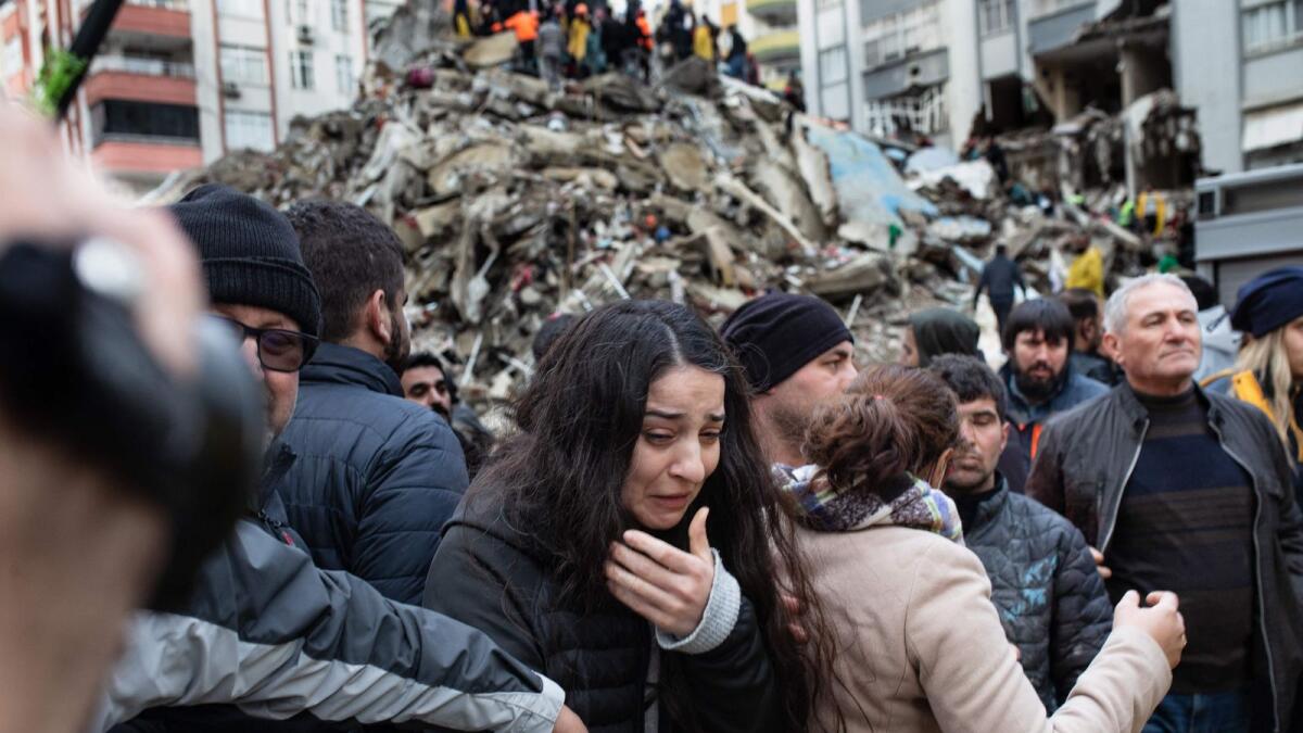 A woman reacts as rescuers search for survivors through the rubble of collapsed buildings in Adana after a 7.8 magnitude earthquake struck the country's south-east.