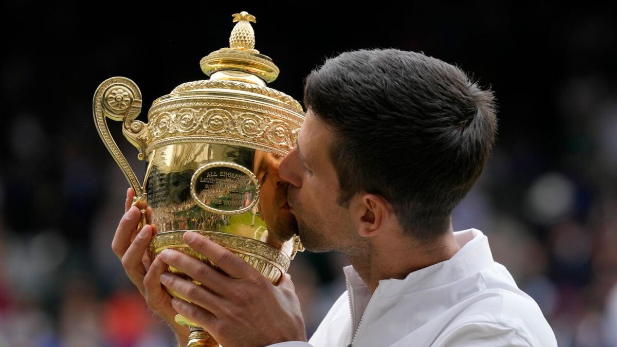 Serbia's Novak Djokovic kisses the winners trophy as he poses for photographers after he defeated Italy's Matteo Berrettini in Wimbledon final. — AP