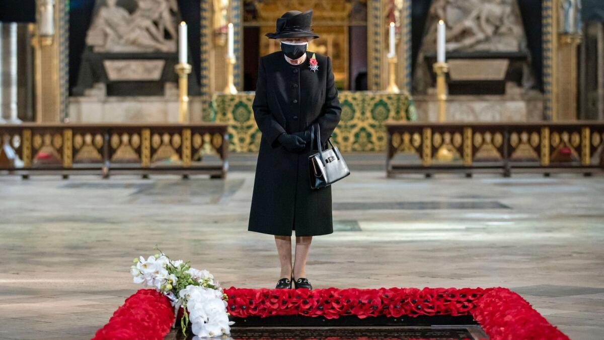 Queen Elizabeth inspects a bouquet of flowers placed on her behalf at the grave of the Unknown Warrior by her Equerry, Lieutenant Colonel Nana Kofi Twumasi-Ankrah, during a ceremony in Westminster Abbey, London.