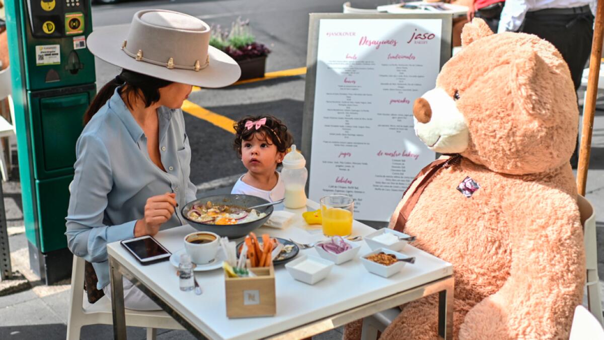 Customers sit with a teddy bear used to keep social distancing measures, during the gradual reopening of commercial activities amid the novel coronavirus pandemic, at a restaurant in Polanco neighborhood, in Mexico City, on July 26, 2020. Photo: AFP
