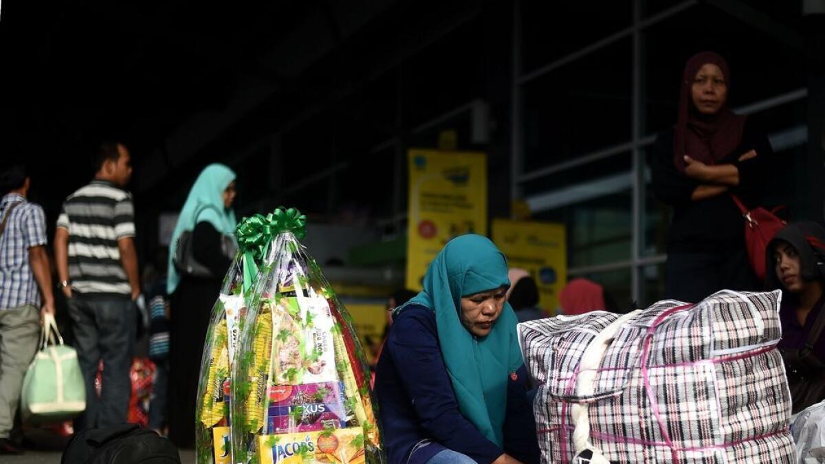 An Indonesian woman does last-minute packing as she waits to board a ferry to head home ahead of the Eid al-Fitr festival