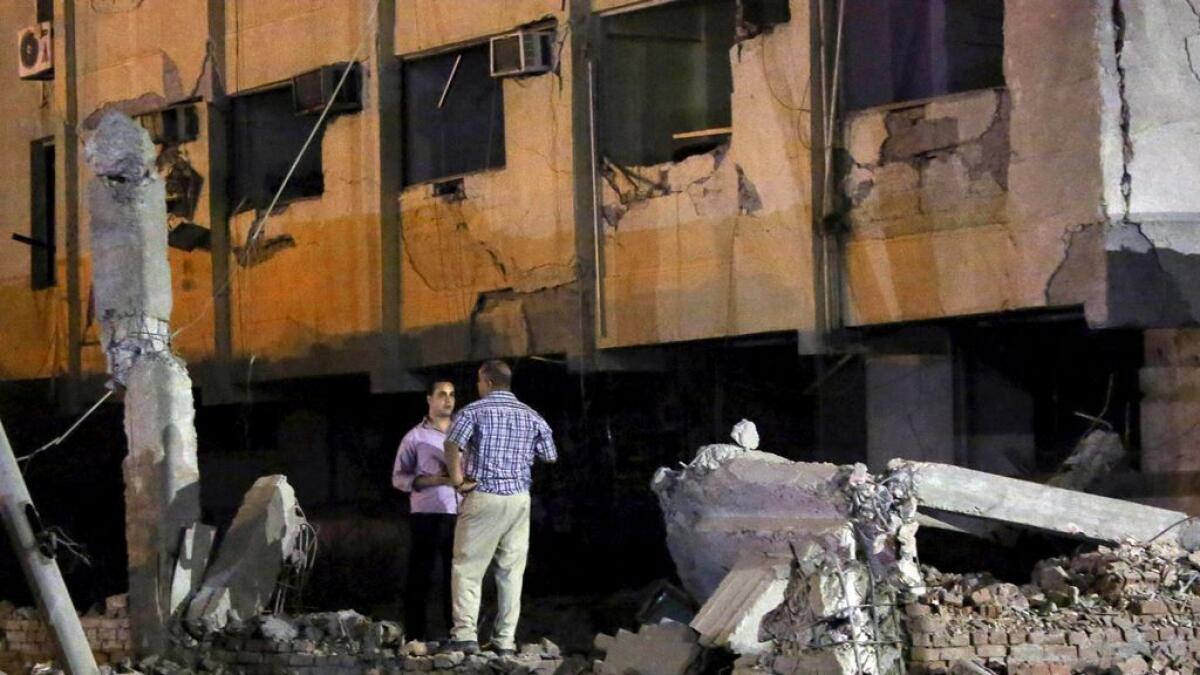 Security officials stand at the site of a bomb blast at a national security building in Shubra Al-Khaima on the outskirts of Cairo, Egypt 