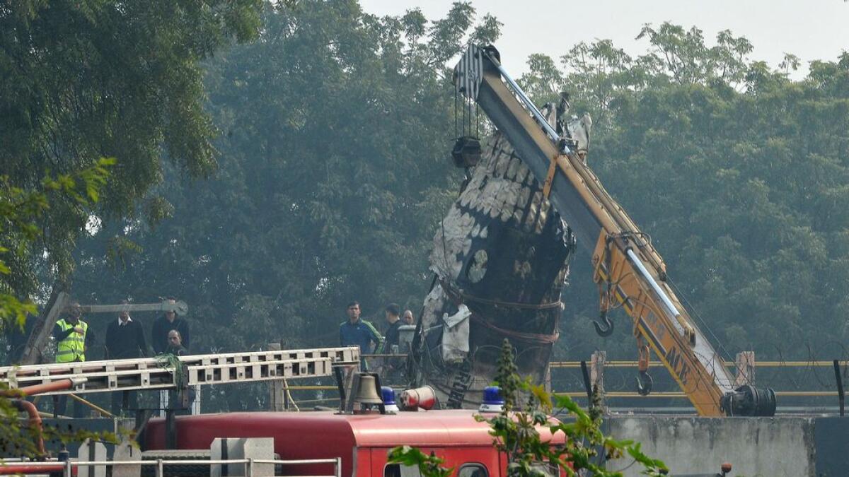A piece of plane wreckage is hoisted by a crane as rescue personel look on at the crash site of a chartered army plane close to the main airport in New Delhi.   