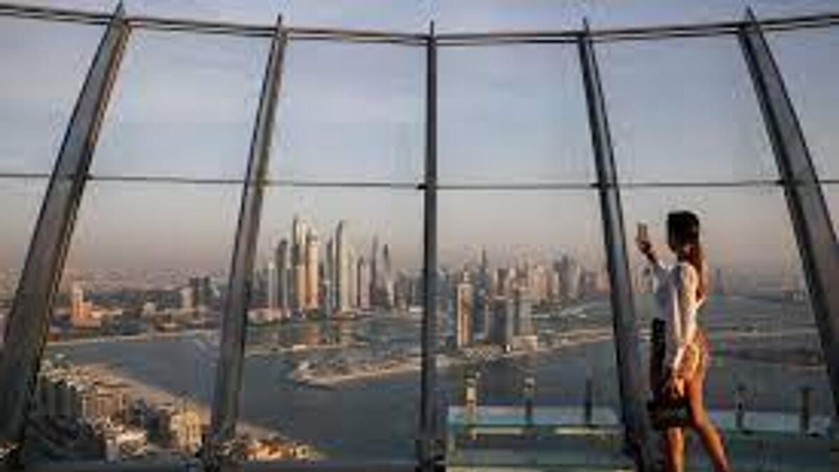 A woman takes a picture with a smartphone of the upscale Marina district from the Palm Tower in Dubai. — Reuters