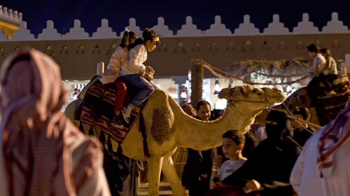 Saudi children ride a camel at Al Qasim pavilion, during the 32nd Janadriyah Culture and Heritage Festival. — AFP