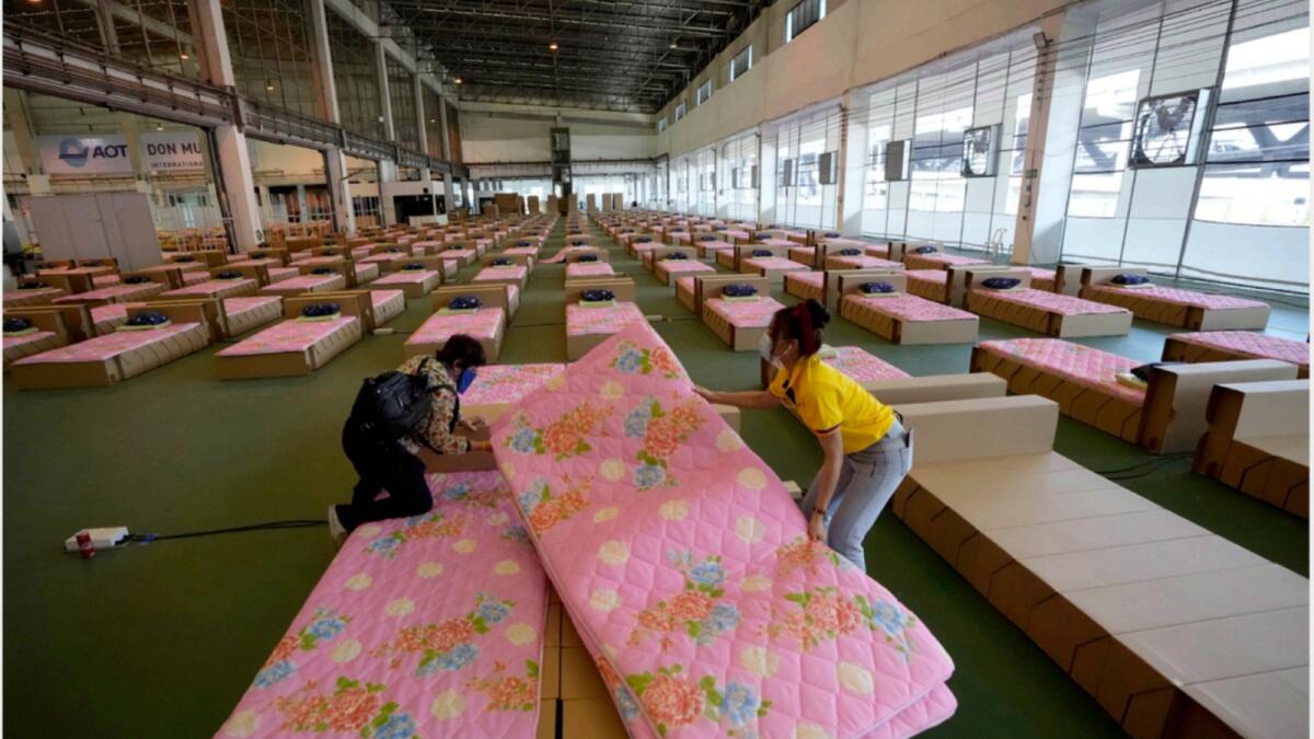 A volunteer and a worker prepare a 1,800-bed field hospital set up inside a cargo building in Don Mueang International Airport in Bangkok, Thailand. — AP