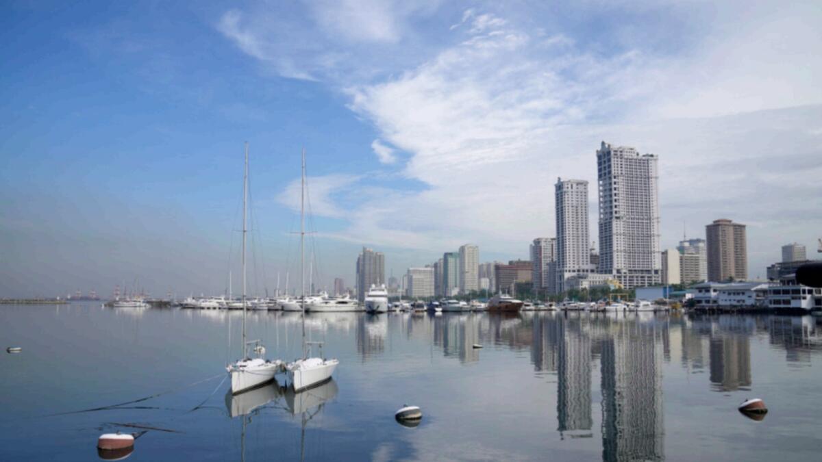 Buildings are reflected beside docked boats in the waters of Manila's bay. — AP