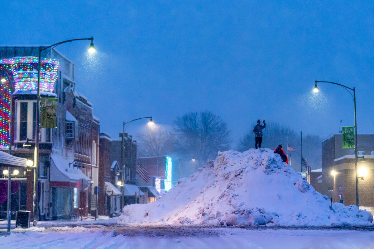 People play on an large snow pile in Oskaloosa, Iowa, on Tuesday. — AP