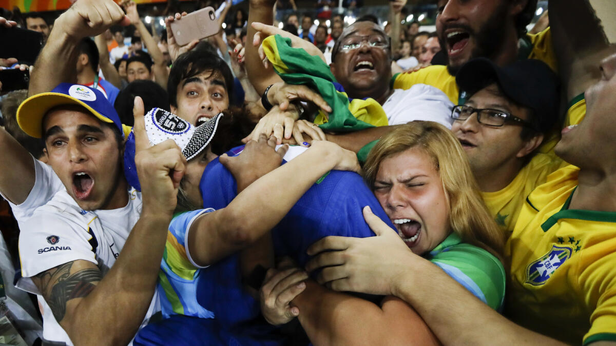 FILE - In this Monday, Aug. 8, 2016 file photo, Brazil's Rafaela Silva, center, celebrates with supporters after winning the gold medal of the women's 57-kg judo competition at the 2016 Summer Olympics in Rio de Janeiro, Brazil. Judo champion Silva grew up in Cidade de Deus. If not for the sport that helped her climb up and out, ?I could still be living in City of God now,? she said through tears after winning on Monday. (AP Photo/Markus Schreiber, File)