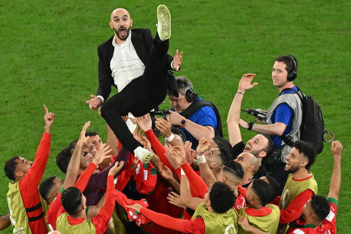Morocco's players throw Morocco's coach Walid Regragui in the air as they celebrate at the end of the Qatar 2022 World Cup round of 16 football match between Morocco and Spain at the Education City Stadium in Al-Rayyan, west of Doha on December 6, 2022. Photo: AFP