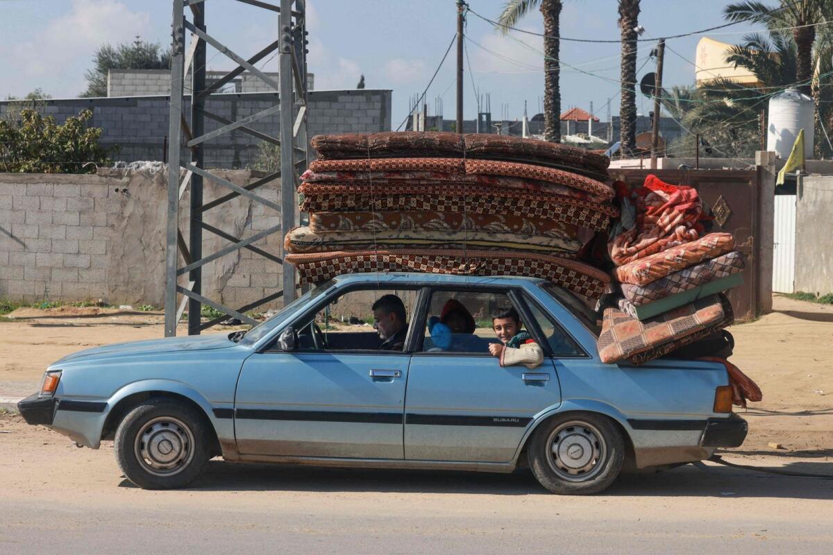 People carrying some of their belongings arrive in Rafah on the southern Gaza Strip on Thursday. — AFP