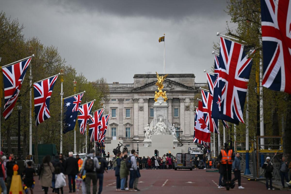 People walk beneath flags of the Union and Commonwealth on The Mall, looking towards Buckingham Palace, in central London. Photo: AFP